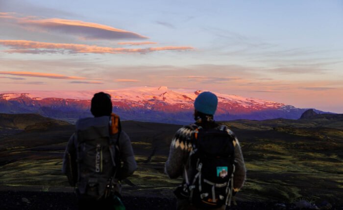 two hikers enjoying sunrise on eyjafjallajökull, Icelandic landscape with glacier