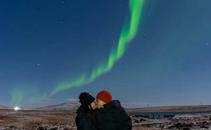 two people kissing with northern lights above them