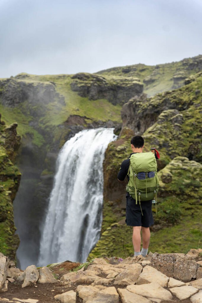 Hiker looking at a waterfall along the Skógá river on the Fimmvörðuháls trail