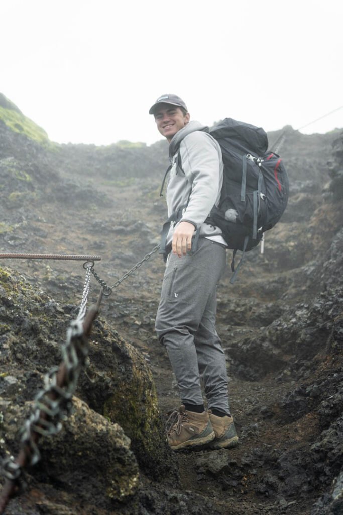 Hiker descending a steep section of the Fimmvörðuháls trail holding a chain