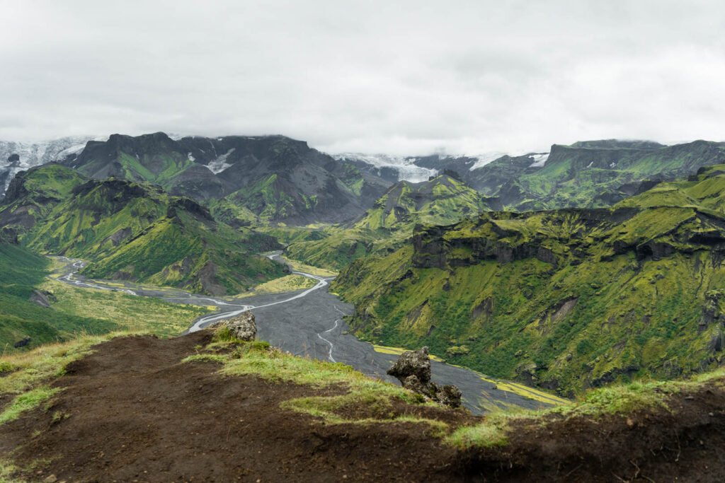 View over the green Þórsmörk valley with moss, braided rivers and a glacier behind