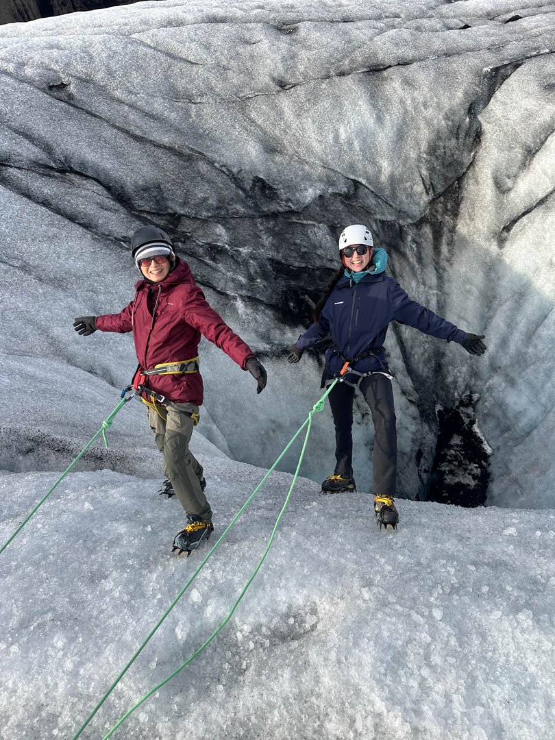 Two hikers on a rope next to a moulin on Sólheimajökull glacier